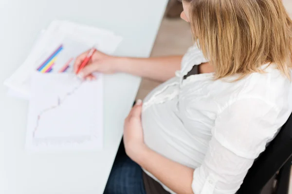 Gravid kvinna med handen på magen kontrollera rapporter — Stockfoto