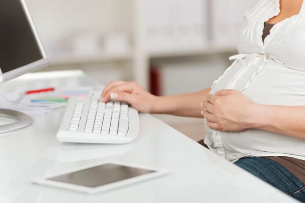 컴퓨터를 사용 하 여 테이블에 배꼽에 손 가진 임신한 여자 — 스톡 사진