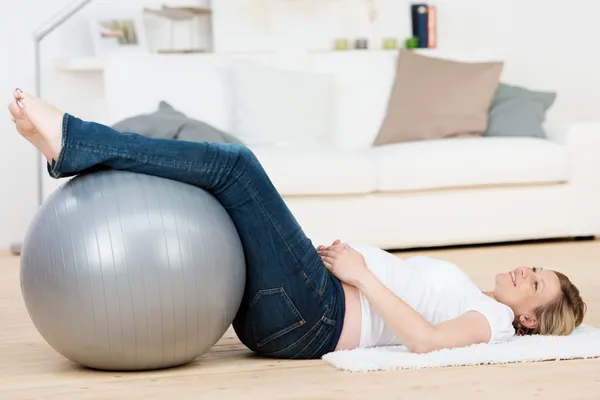 Mujer embarazada haciendo ejercicio con pilates mientras está acostada en el suelo — Foto de Stock