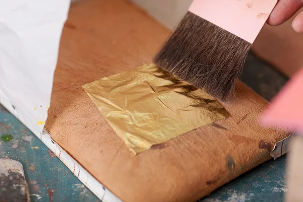 Frau benutzt goldenes Metallblatt in Werkstatt — Stockfoto