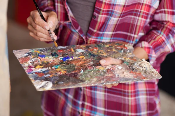 Mulher que mistura a pintura na paleta — Fotografia de Stock