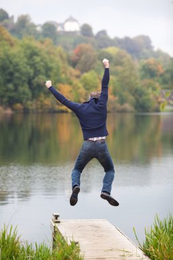 Excited Man Jumping On Pier clipart