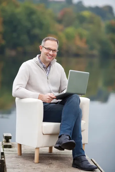 Volwassen man met laptop tijdens de vergadering op de pier — Stockfoto