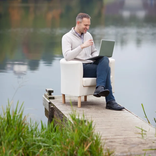 Άνθρωπος χρησιμοποιώντας φορητό υπολογιστή κατά τη λίμνη — Φωτογραφία Αρχείου