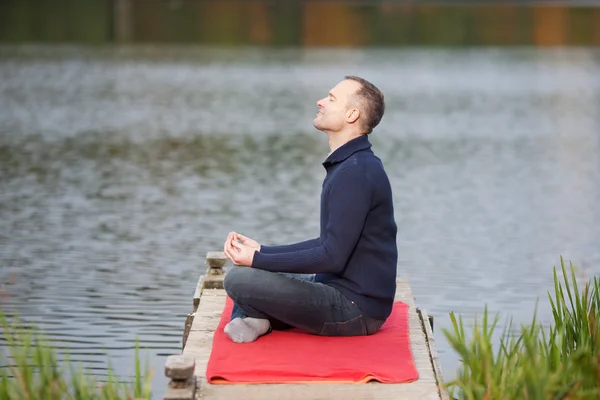 Man mediteren in lotus positie op pier tegen lake — Stockfoto