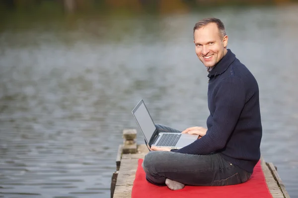 Homme souriant avec ordinateur portable en plein air — Photo