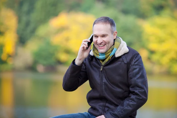 Человек, использующий мобильный телефон, глядя в сторону озера — стоковое фото
