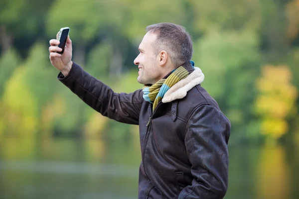 Uomo in giacca prendendo autoritratto attraverso il telefono cellulare — Foto Stock