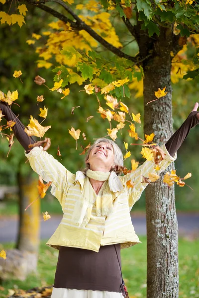 Herbstlaub fällt auf Seniorin — Stockfoto