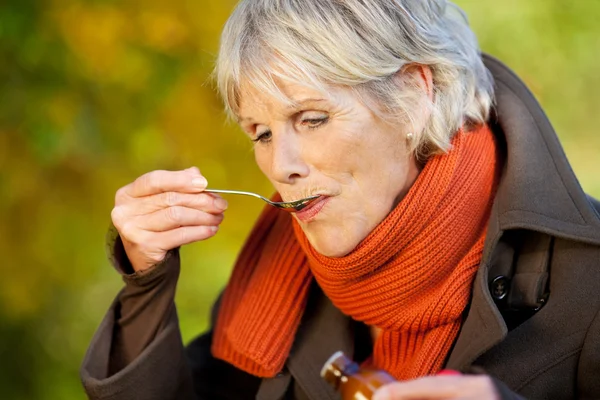 Äldre kvinna dricka sockerlag på park — Stockfoto