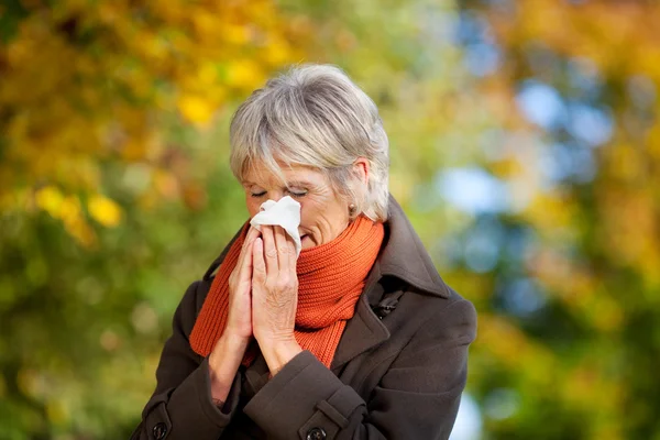 Senior vrouw lijden aan koude in park — Stockfoto