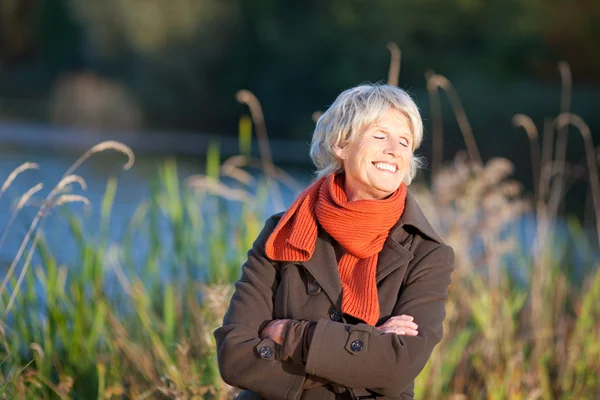 Senior vrouw genieten van zonlicht in park — Stockfoto