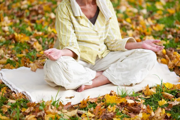 Mulher sênior meditando na posição de lótus no parque — Fotografia de Stock