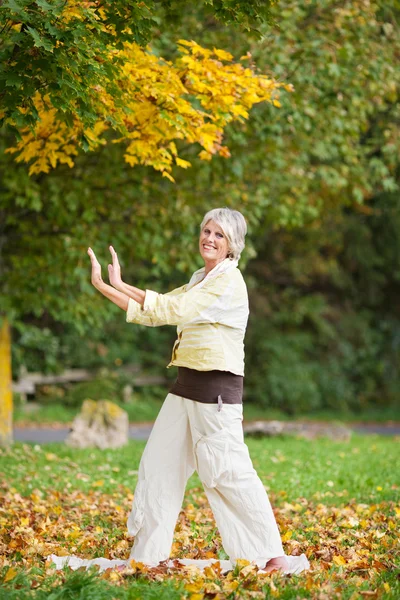Sorrindo mulher sênior com braços levantados fazendo Yoga — Fotografia de Stock