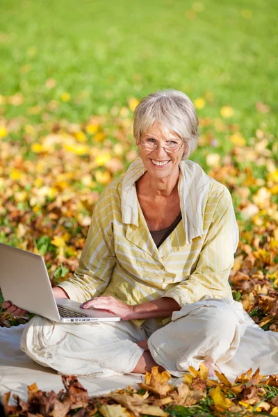 Kvinna med laptop medan du sitter i park — Stockfoto