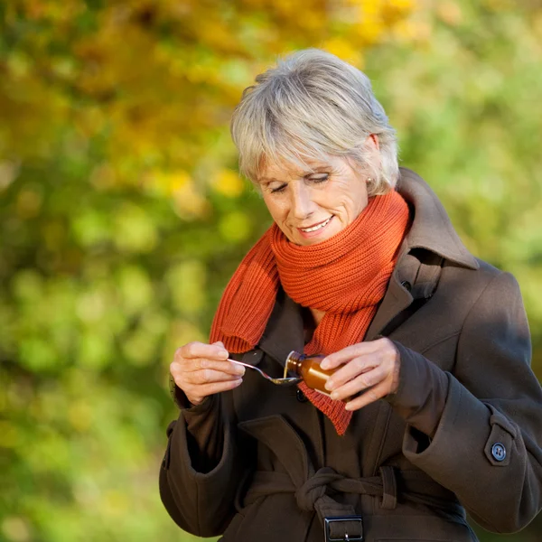 Senior vrouw gieten in lepel siroop — Stockfoto