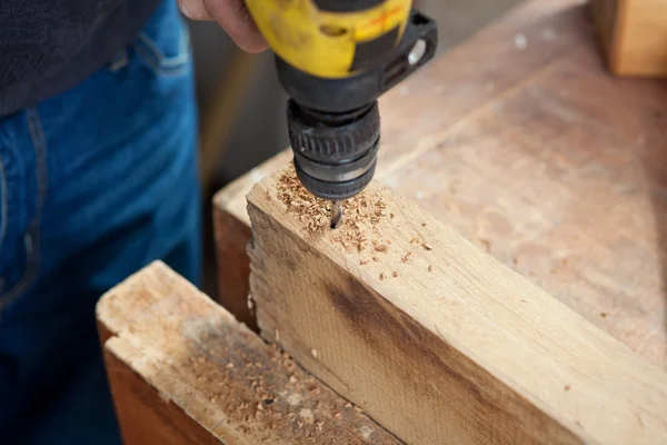 Tahta parçası üzerinde delme makinesi kullanarak bir marangoz — Stok fotoğraf