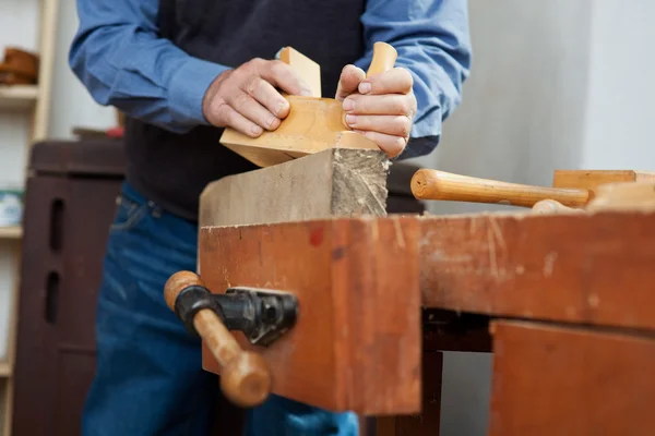 Falegname che utilizza pialla su legno al banco da lavoro — Foto Stock