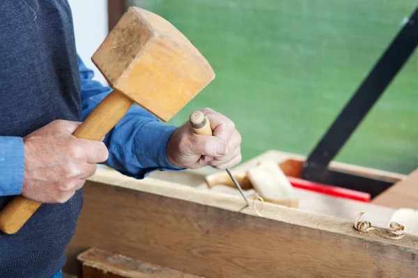 Senior Man Using Chisel And Hammer On Wood Stockfoto