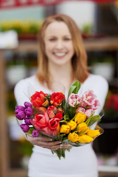 魅力的な若い女性は花の束を示す — ストック写真