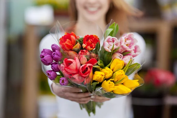 Mulher mostrando um monte de flores sortidas — Fotografia de Stock