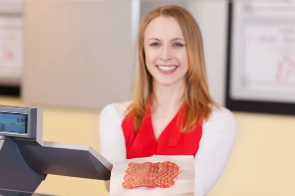 Schöne Verkäuferin bietet geschnittene Salami an — Stockfoto