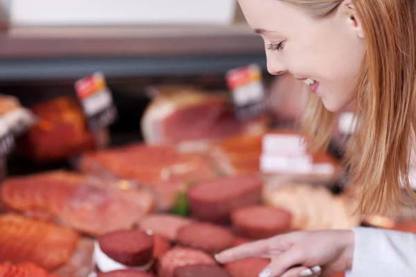 Smiling female customer selecting sausages — Stock Photo, Image