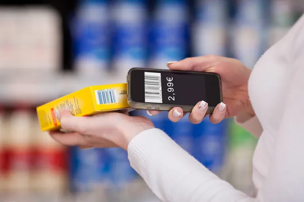 Mãos de mulher digitalizando código de barras com telefone celular no supermercado — Fotografia de Stock