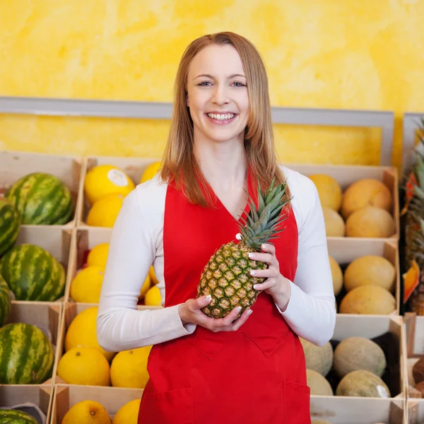 Arbeiterin hält Ananas in Lebensmittelgeschäft — Stockfoto