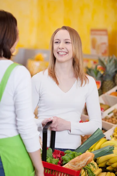 Kvinna som bär kundvagnen medan du tittar på arbetstagare i butik — Stockfoto