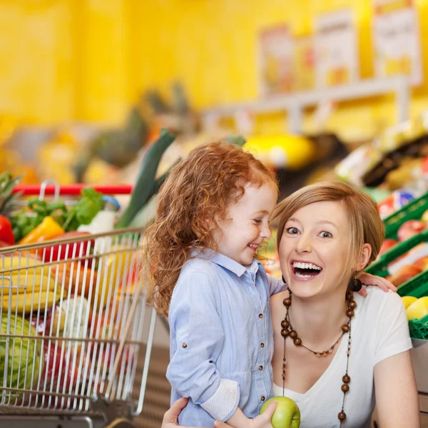 Skrattande mor och dotter i en stormarknad — Stockfoto