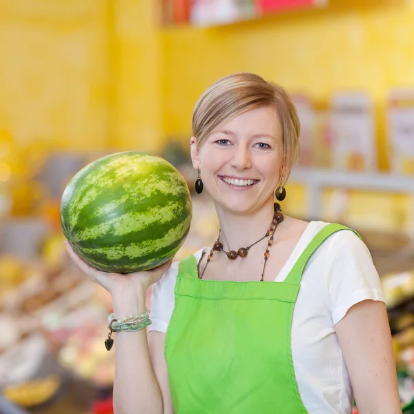 Женщина-рабочий держит арбуз в продуктовом магазине — стоковое фото