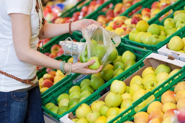 Vrouwelijke klant groene appels plukken om te kopen — Stockfoto