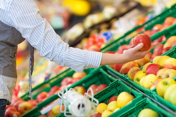 Frau sucht Äpfel an der Lebensmitteltheke aus — Stockfoto