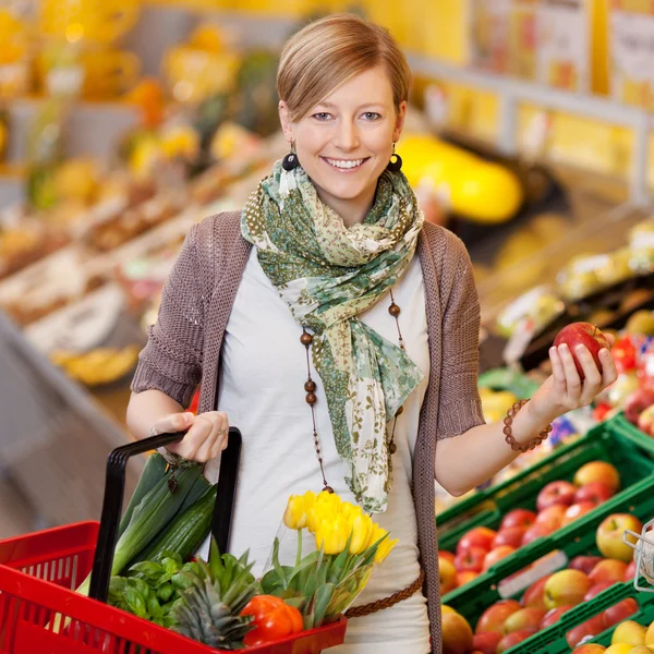 Улыбающаяся женщина покупает свежие продукты — стоковое фото