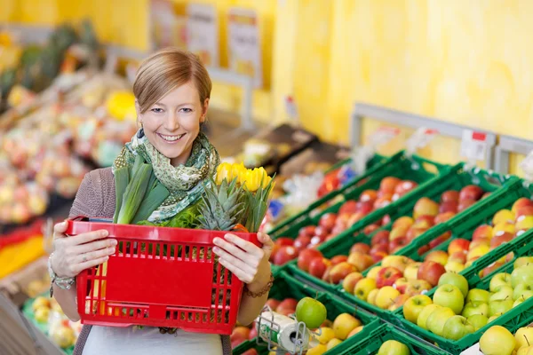 Frau trägt Einkaufskorb in Lebensmittelgeschäft — Stockfoto