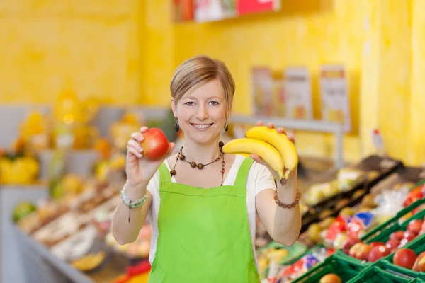 Friendly saleswoman showing different fruits — Stock Photo, Image