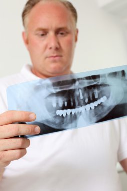 Male Dentist Analyzing Xray In Clinic clipart