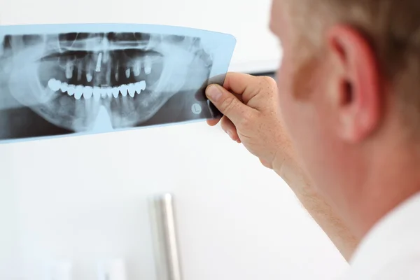 Dentista mirando rayos X dentales — Foto de Stock