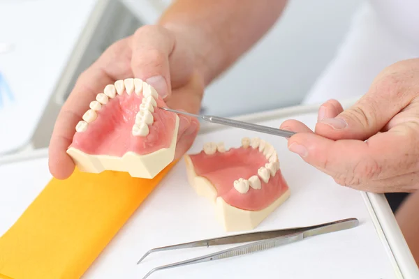 Mężczyzna dentysta wyjaśniając stomatologiczne oddanych w klinice — Zdjęcie stockowe