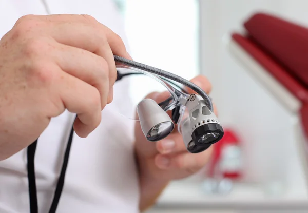 Стоматолог держит медицинские очки в клинике — стоковое фото
