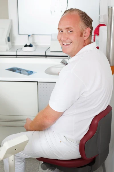 Confident dentist sitting in clinic — Stock Photo, Image