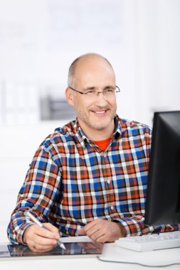 Mature man smiling when working at the office clipart