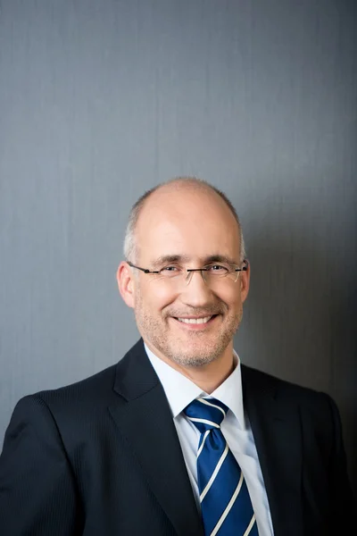 Businessman Smiling Against Gray Wall — Stock Photo, Image