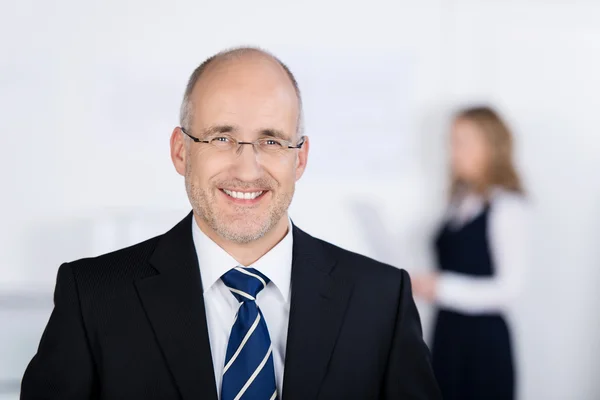 Empresário confiante sorrindo com colega de trabalho no fundo — Fotografia de Stock