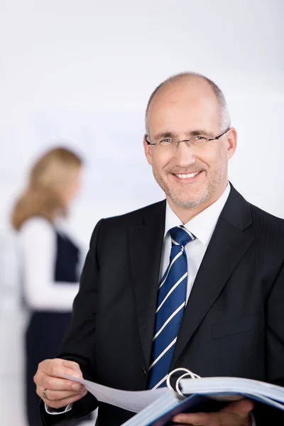 Businessman Holding Binder With Coworker In Background — Stock Photo, Image