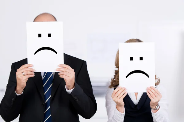 Empresários segurando Smileys Tristes em Placard na frente de rostos — Fotografia de Stock