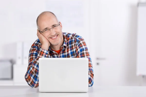 友好的成熟男人，微笑着用一台笔记本电脑 — 图库照片