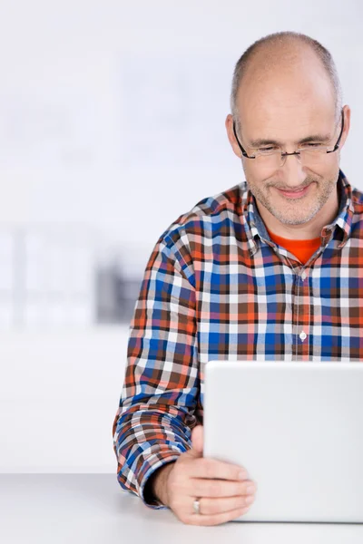 Dojrzały człowiek uśmiechający się patrząc na laptopa — Zdjęcie stockowe