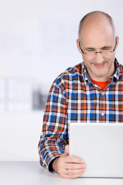 Uomo maturo sorridente quando guarda il computer portatile — Foto Stock